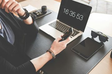 Woman Using a Smartphone While Fronting a Macbook Pro and Black Ipad